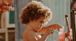 Little child with kinky afro hair painting.